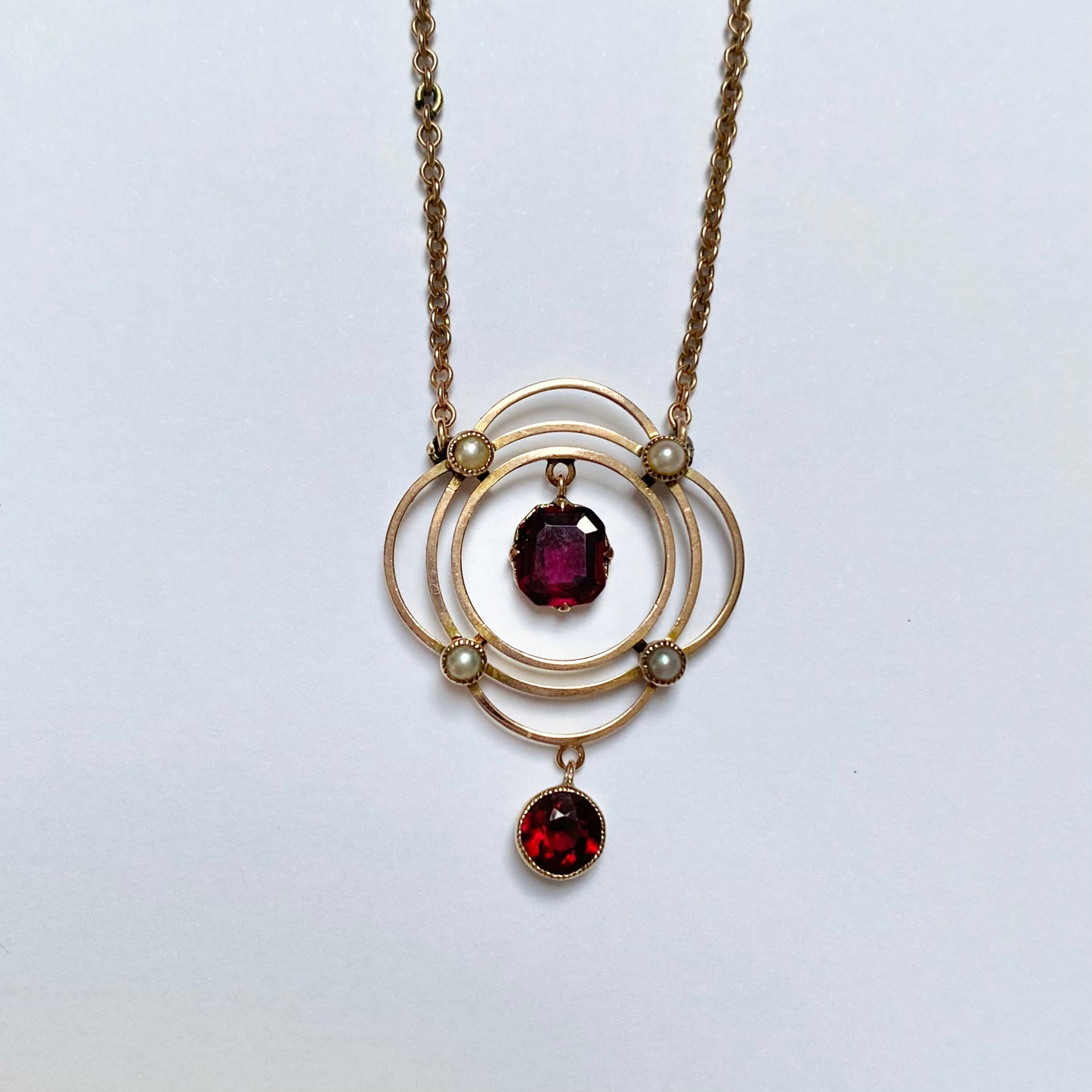 Early 20th garnet and split pearl scalloped pendant, with integral chain,