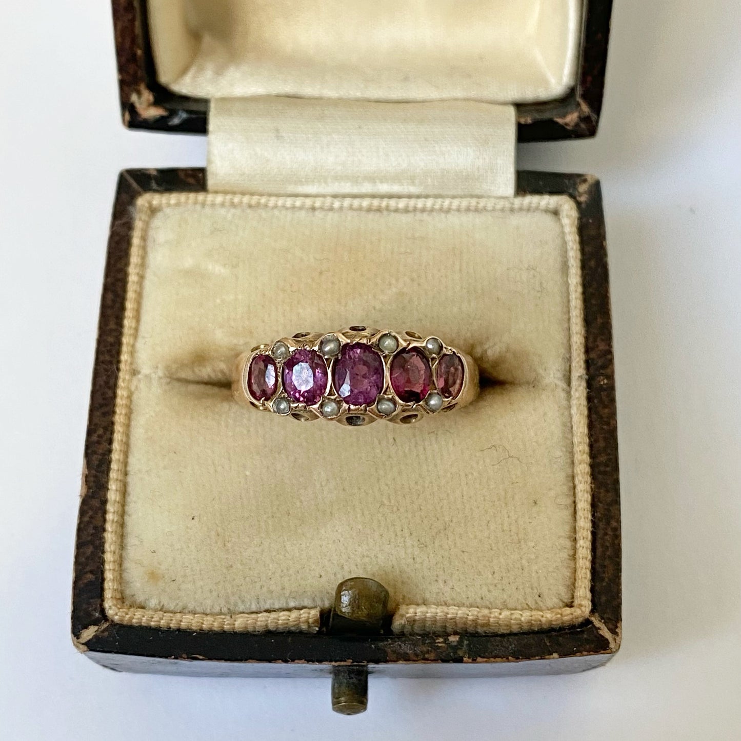 An early 20th century gold garnet five-stone ring, with seed pearl highlights.