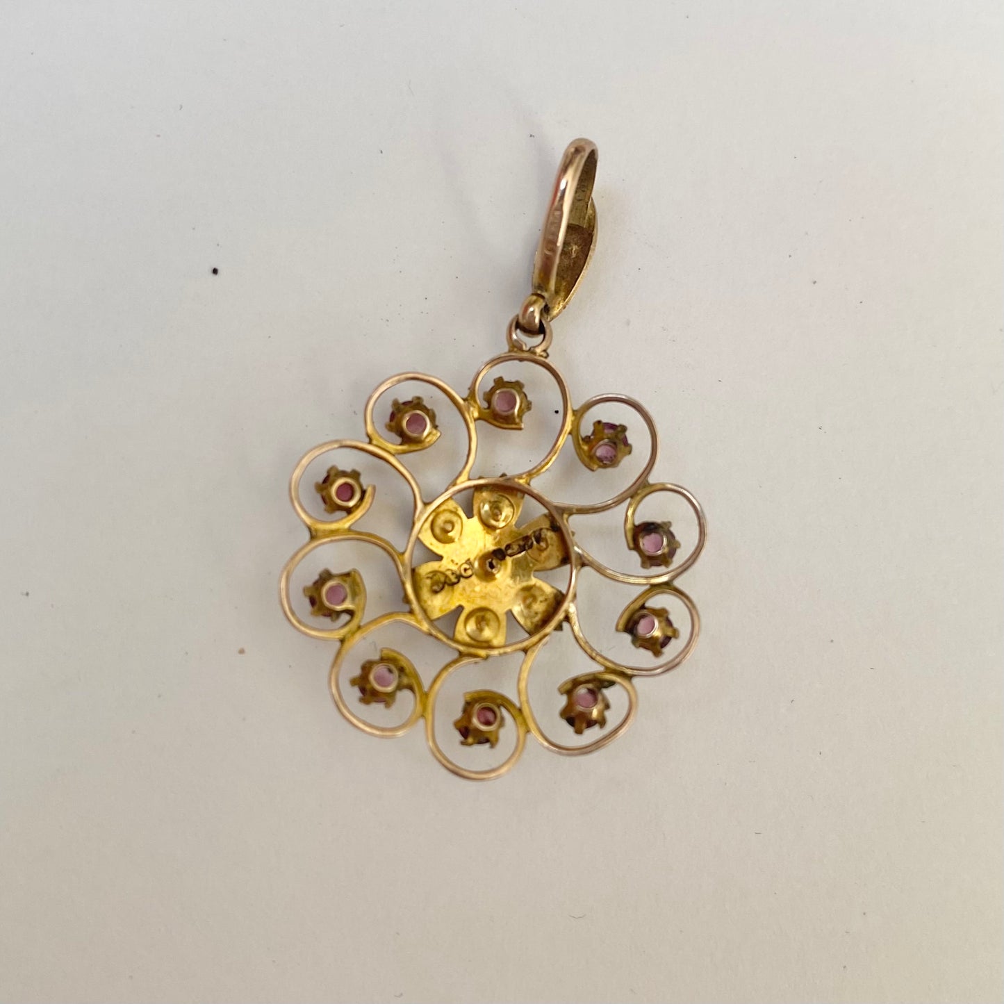 An early 20th century naturalistic 9ct gold garnet and split pearl wreath pendant.