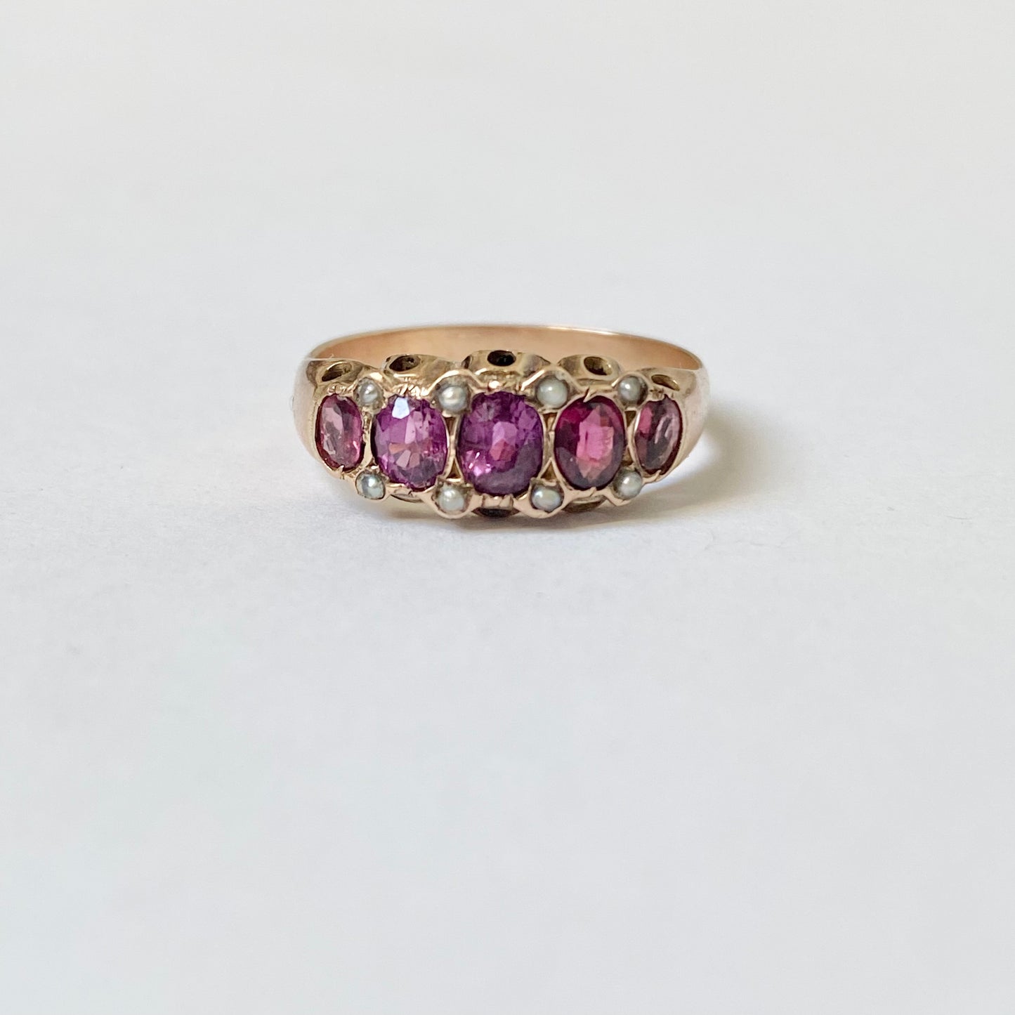 An early 20th century gold garnet five-stone ring, with seed pearl highlights.