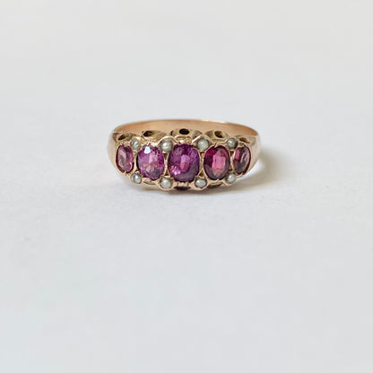 An early 20th century gold garnet five-stone ring, with seed pearl highlights.