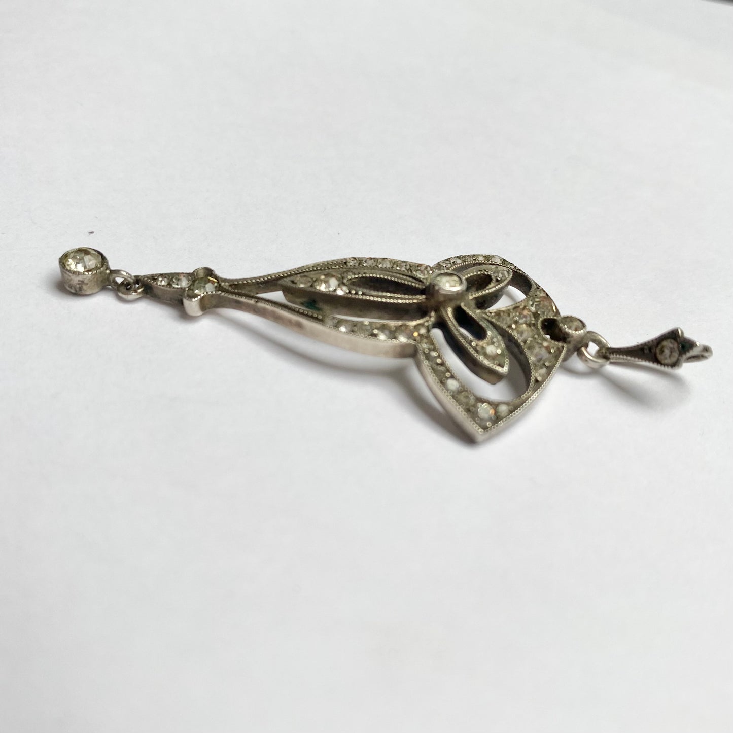 An Edwardian silver colourless paste foliate pendant.