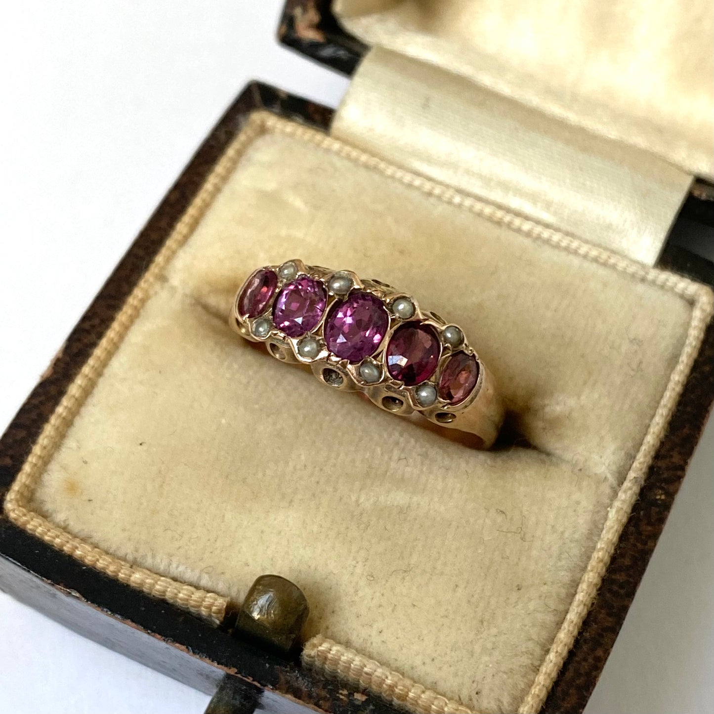 An early 20th century gold garnet five-stone ring, with seed pearl highlights.