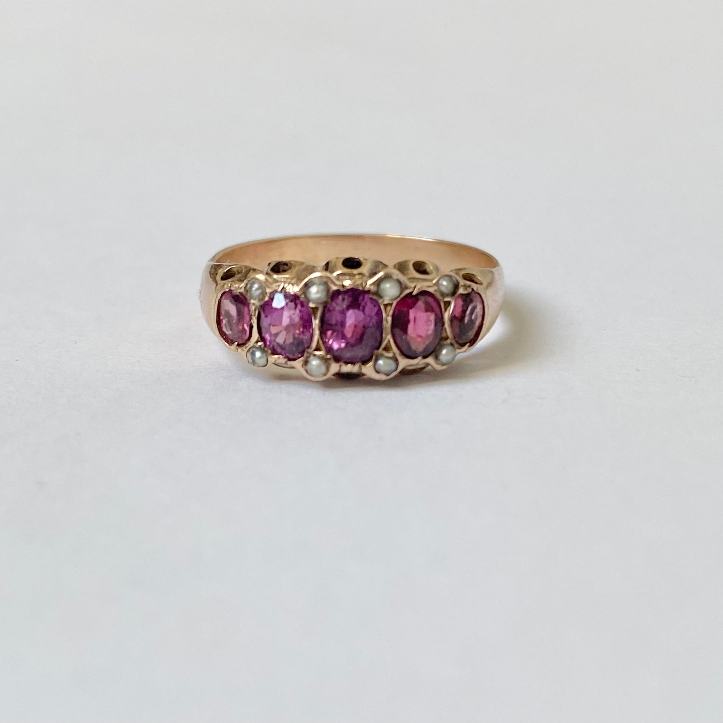 An early 20th century gold garnet five-stone ring, with seed pearl highlights.