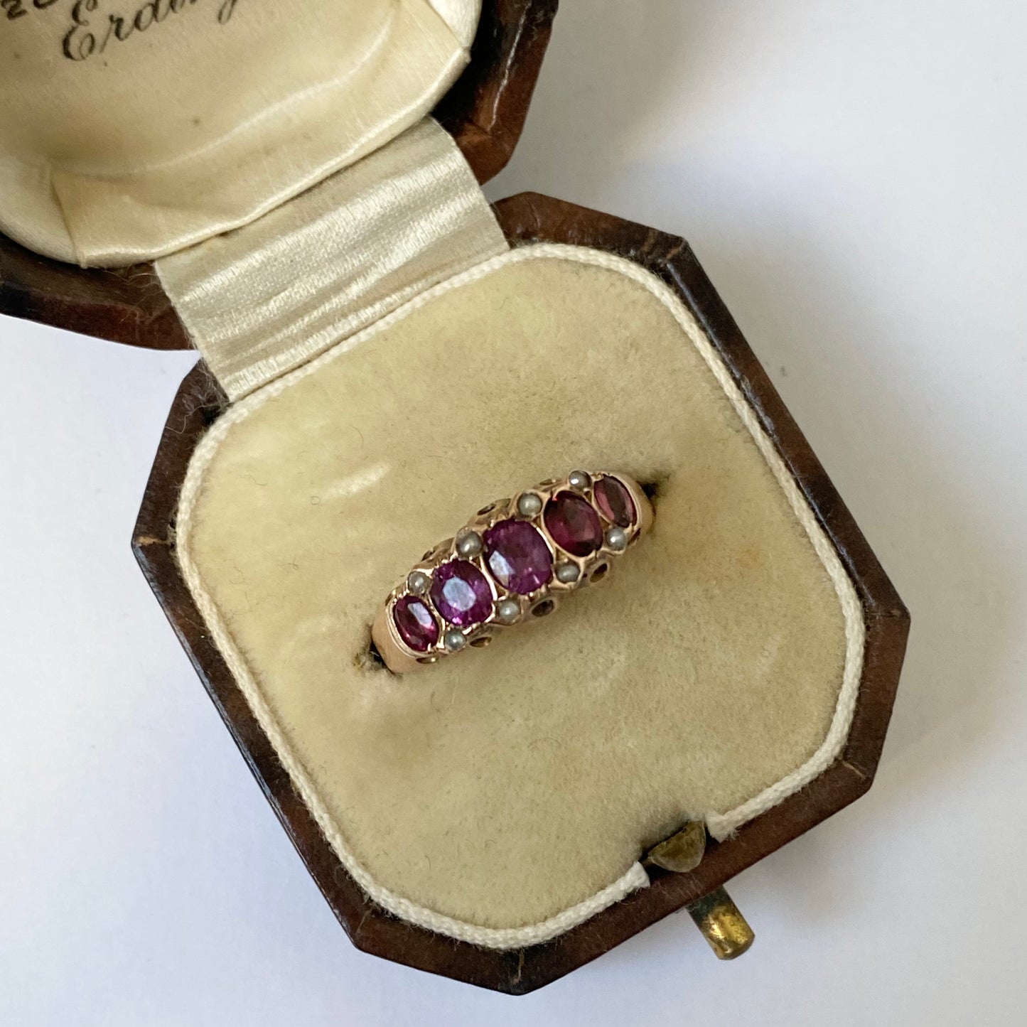 An early 20th century gold garnet five-stone ring, with seed pearl highlights.
