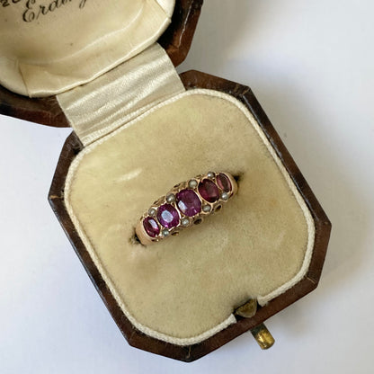 An early 20th century gold garnet five-stone ring, with seed pearl highlights.
