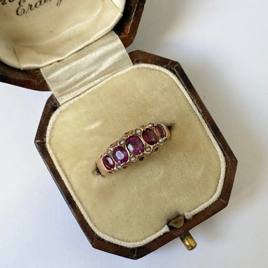 An early 20th century gold garnet five-stone ring, with seed pearl highlights.