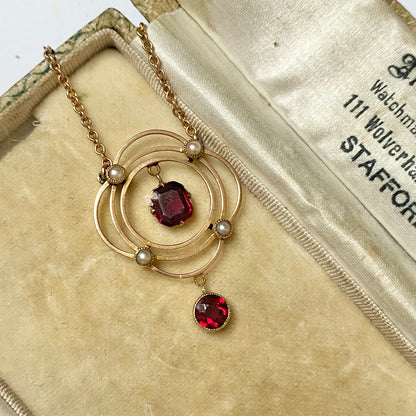 Early 20th garnet and split pearl scalloped pendant, with integral chain,