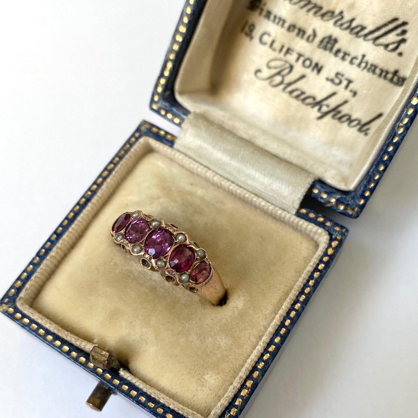 An early 20th century gold garnet five-stone ring, with seed pearl highlights.