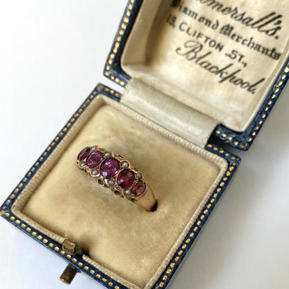 An early 20th century gold garnet five-stone ring, with seed pearl highlights.
