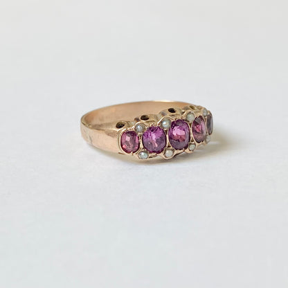 An early 20th century gold garnet five-stone ring, with seed pearl highlights.