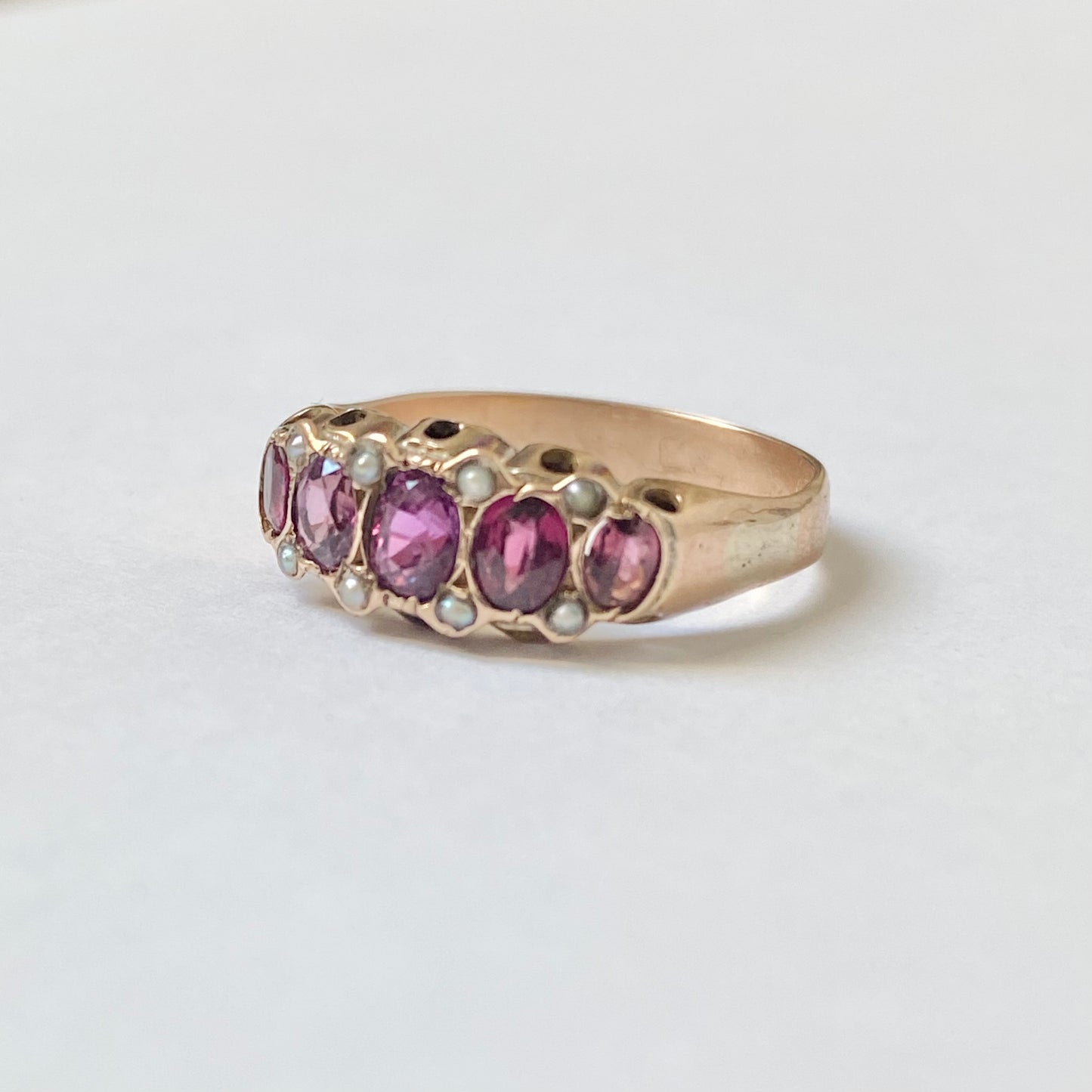 An early 20th century gold garnet five-stone ring, with seed pearl highlights.