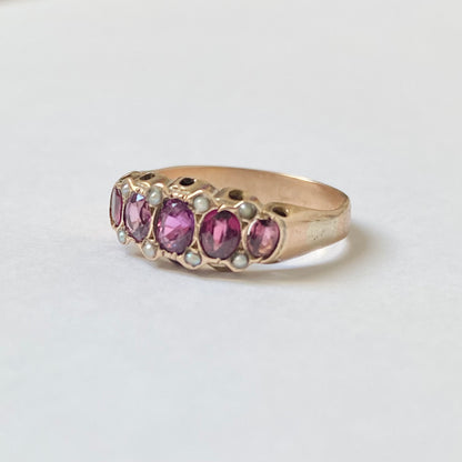 An early 20th century gold garnet five-stone ring, with seed pearl highlights.