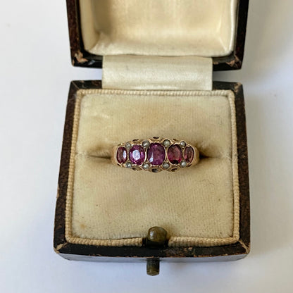 An early 20th century gold garnet five-stone ring, with seed pearl highlights.