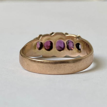 An early 20th century gold garnet five-stone ring, with seed pearl highlights.